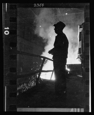 16.-Steel-worker-standing-in-mill-with-smelter-in-the-background-in-Chicago-Illinois
